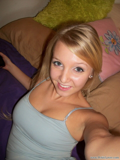 Cute teen girl with blonde hair displays her hairless pussy on her bed