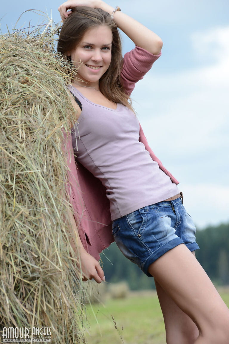 Pretty brunette Rumba squats naked in a hay field to reveal her shaved pussy page 1